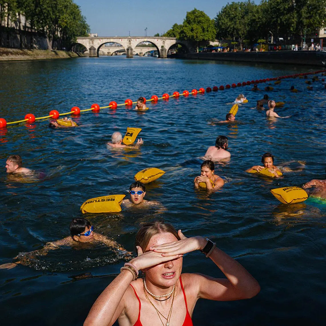 TOPSHOT - People swim at the Bras Marie safe bathing site on the river Seine in Paris on August 12, 2025. France continues to suffocate with 14 departments in the southwest and southeast on red alert for heatwave on August 12, 2025, an exceptional heat wave, even for the month of August, which is prompting authorities to increase precautionary measures. (Photo by Dimitar DILKOFF / AFP)