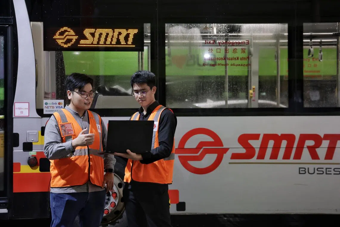 SMRT Buses’ Mr Lee Joonmin (left), 26-year-old senior supervisor, and SIT alumnus Clifford Chong, 25-year-old system integration and support executive, discussing the algorithm the latter created to automate rostering of bus captains at Woodlands Depot on Jan 9, 2024.