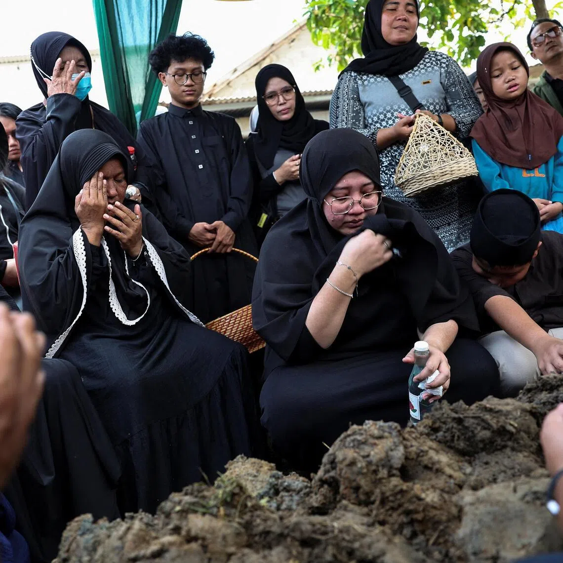 Relatives pray during the funeral of a woman who was killed in the deadly collision between a commuter line train and a long-distance train on April 27, in Bekasi, on the outskirts of Jakarta, Indonesia, on April 29, 2026.