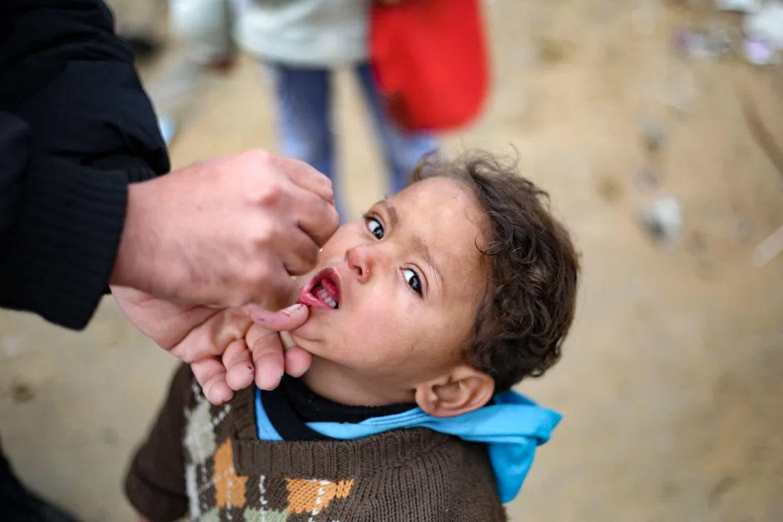 A Palestinian child receives a polio vaccine at a camp for displaced people in Nuseirat in the central Gaza Strip on February 23, 2025, a day after the third mass polio vaccination campaign began in Gaza, with the aim of delivering the first dose to nearly 600,000 children across the Palestinian territory. The vaccination campaign involves multiple UN agencies, including the Israeli-boycotted UN Relief and Works Agency for Palestine refugees (UNRWA), and comes at a time when Israel and Hamas are observing a ceasefire that has largely halted the fighting. (Photo by Eyad BABA / AFP)