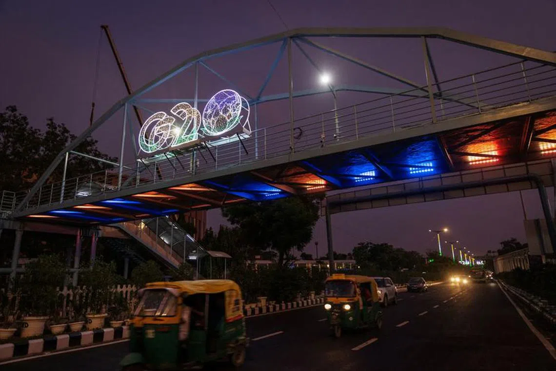 FILE PHOTO: Traffic moves past under a G20 logo installed on a pedestrian bridge in front of the main venue of the summit in New Delhi, India, August 24, 2023. REUTERS/Adnan Abidi/File Photo