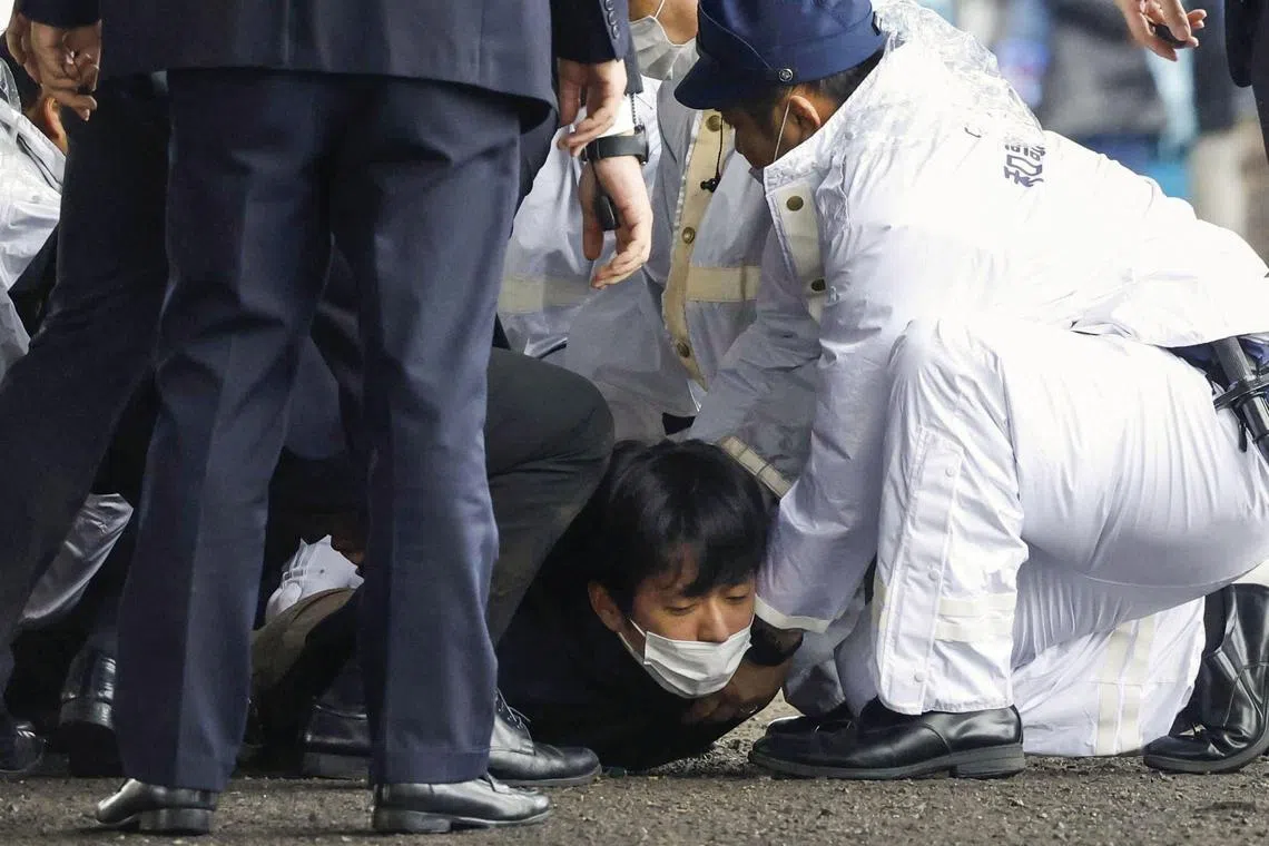 A man, believed to be a suspect who threw a pipe-like object near Japanese Prime Minister Fumio Kishida during his outdoor speech, was held by police officers at Saikazaki fishing port in Wakayama, Japan, on April 15, 2023.