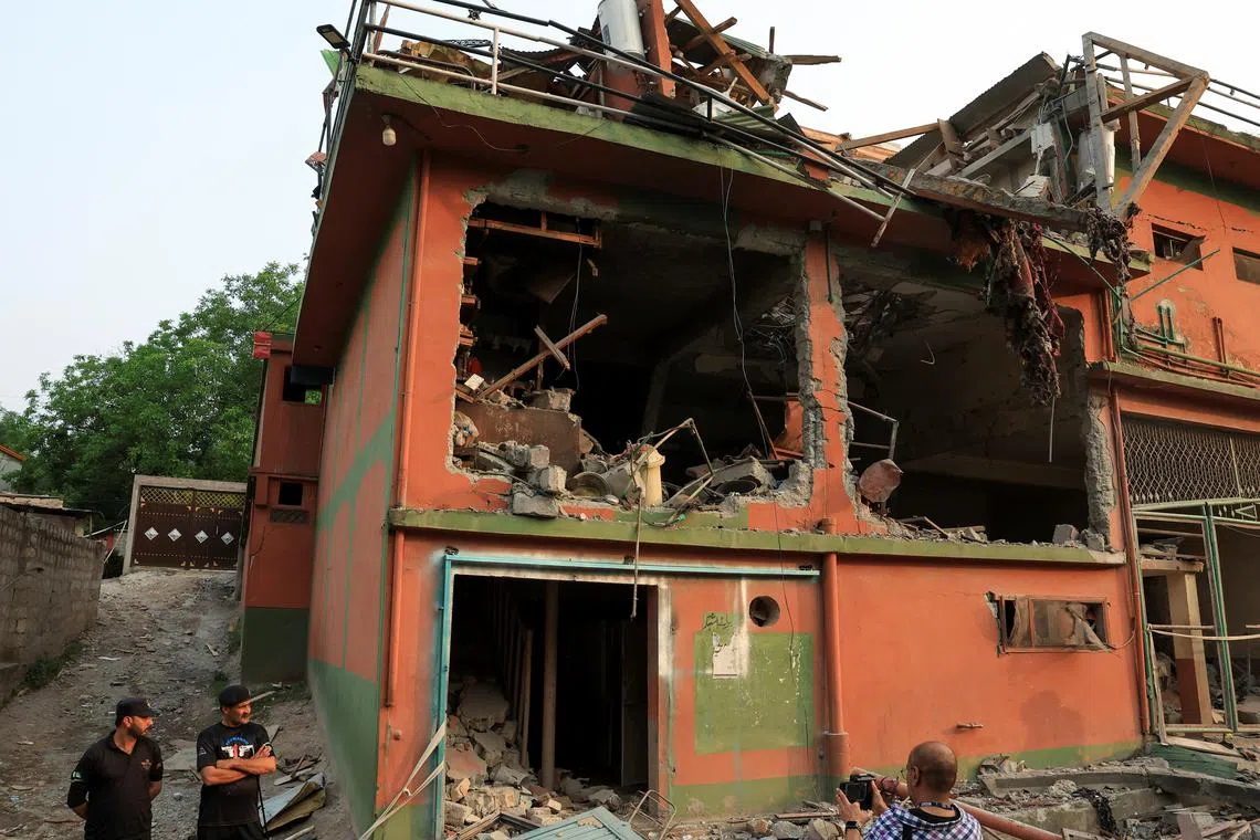 Police officers look on as a cameraman films the Bilal Mosque, after it was hit by an Indian strike in Muzaffarabad, the capital of Pakistan-administered Kashmir, May 7, 2025. REUTERS/Akhtar Soomro