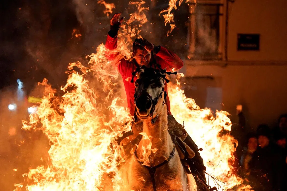 A man rides a horse through flames during the annual "Luminarias" celebration on the eve of Saint Anthony's day, Spain's patron saint of animals, in the village of San Bartolome de Pinares, Spain, January 16, 2025. REUTERS/Ana Beltran     TPX IMAGES OF THE DAY