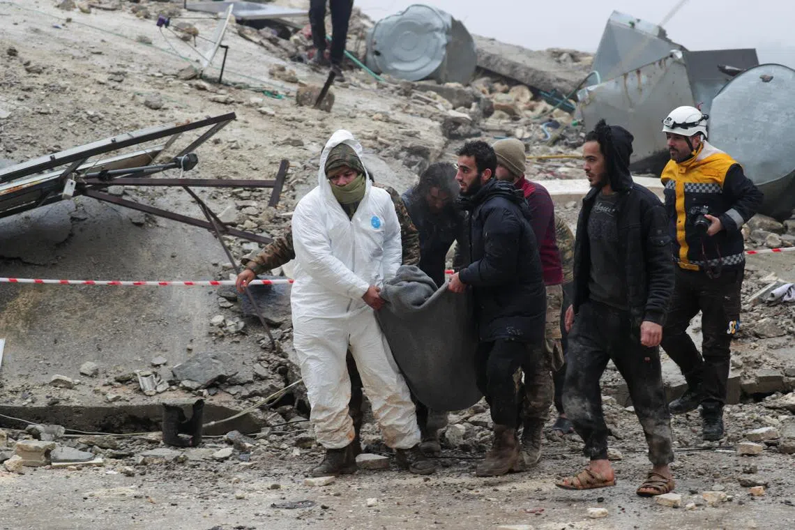 People carry a victim as rescuers search for survivors under the rubble, following an earthquake, in rebel-held town of Jandaris, Syria February 6, 2023. REUTERS/Khalil Ashawi

