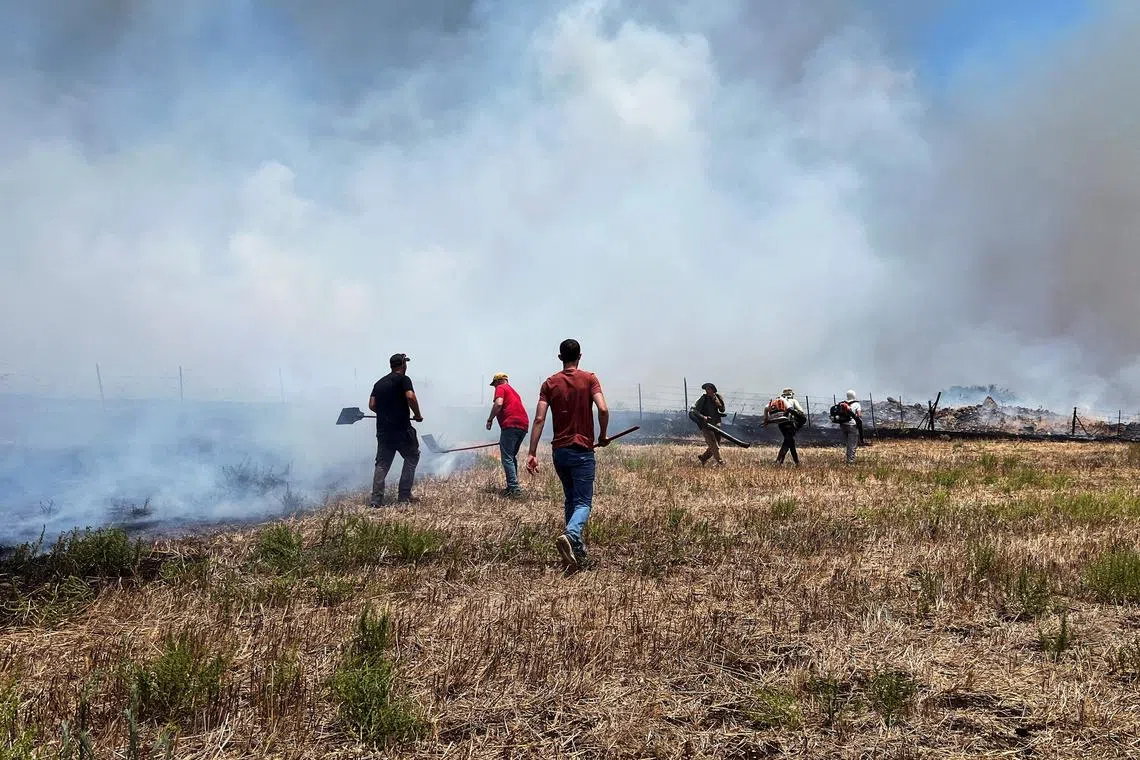 People work to put out fires after Hezbollah launched projectiles at Israel, amid hostilities between Hezbollah and Israeli forces, in the Galilee, northern Israel, July 7, 2024. REUTERS/Avi Ohayon