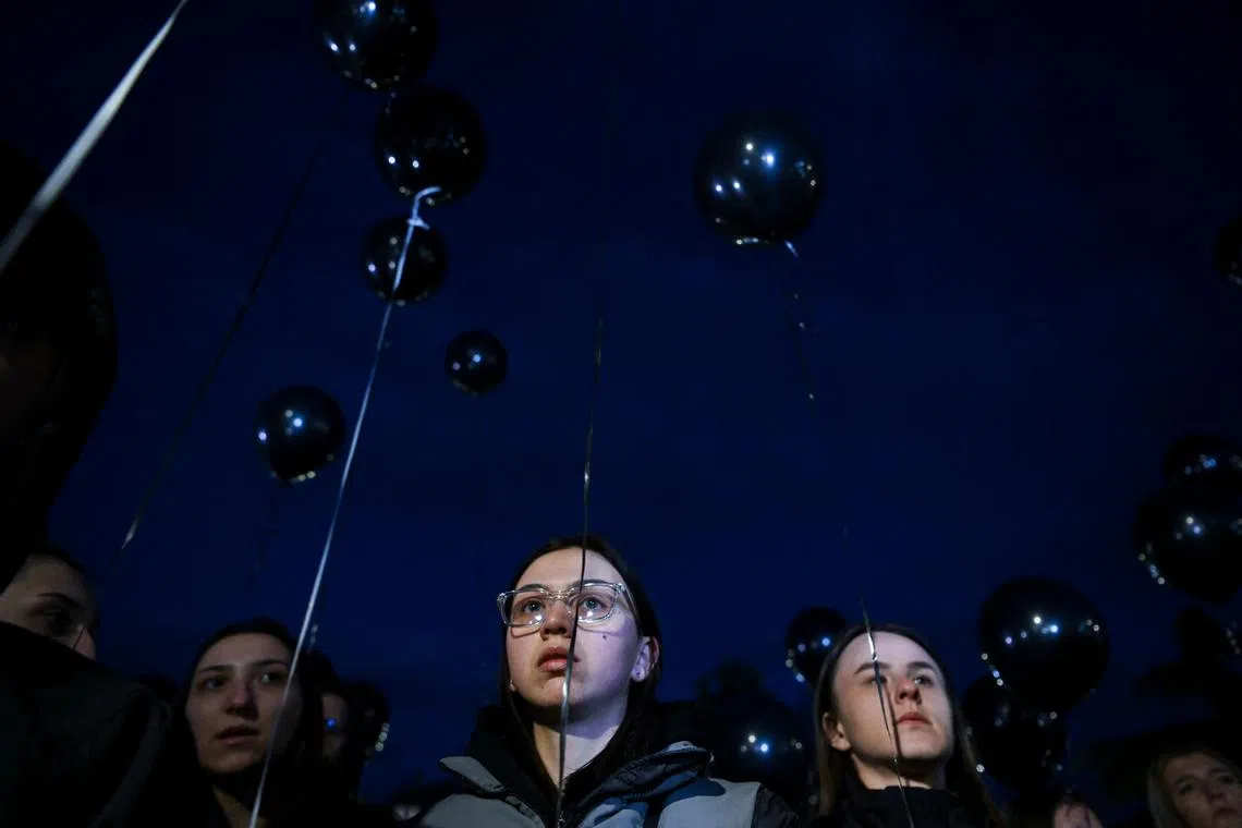 Members of the public holding black balloons during a gathering in tribute to victims of a fire that tore through an overcrowded nightclub killing 59 revellers, in the town of Kocani, North Macedonia, on March 18, 2025.