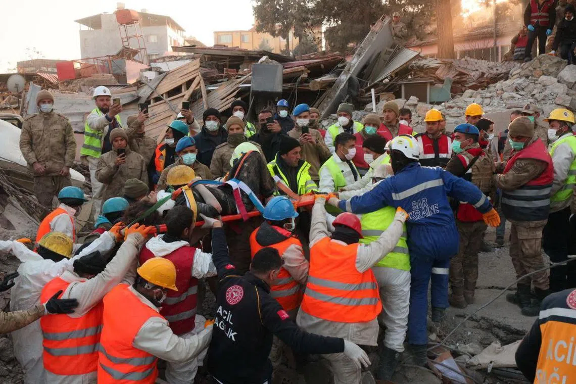 Rescuers carry a woman found under the debris of a collapsed building in Antakya, in Turkey's Hatay province, on Feb 14, 2023.