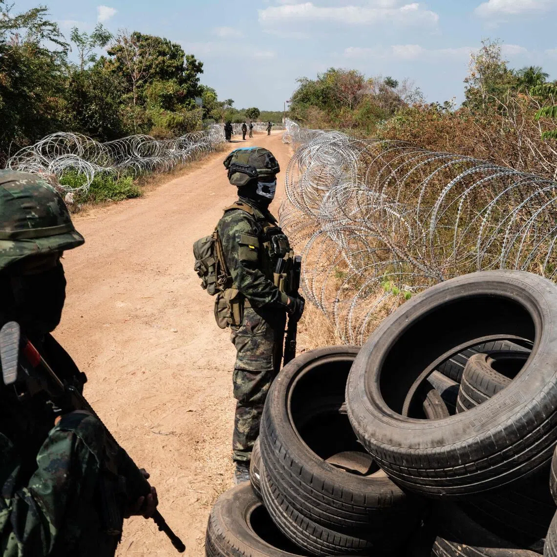Thai soldiers stand guard near barbed wires and tyres installed to mark the border with Cambodia during a military organised tour near Sadok Kok Thom Historical Park on Feb 5.