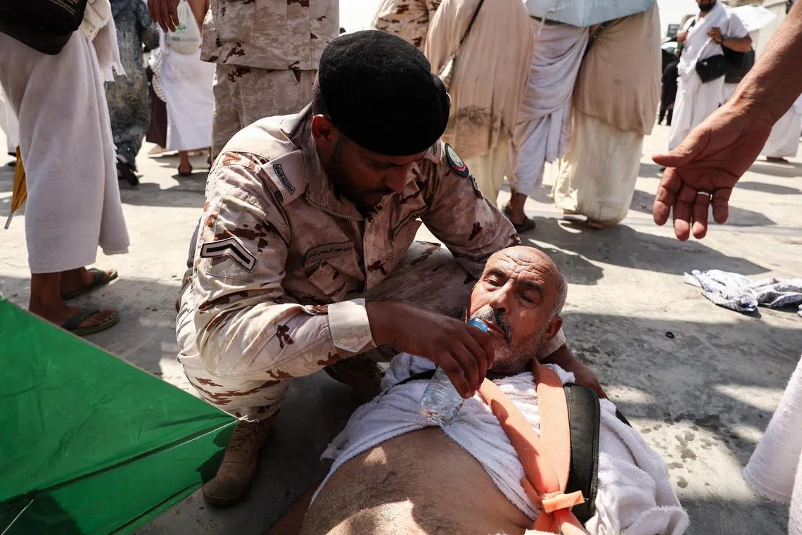 A man affected by the scorching heat in Mina, near Saudi Arabia's holy city of Mecca, is helped by a member of the Saudi security forces.
