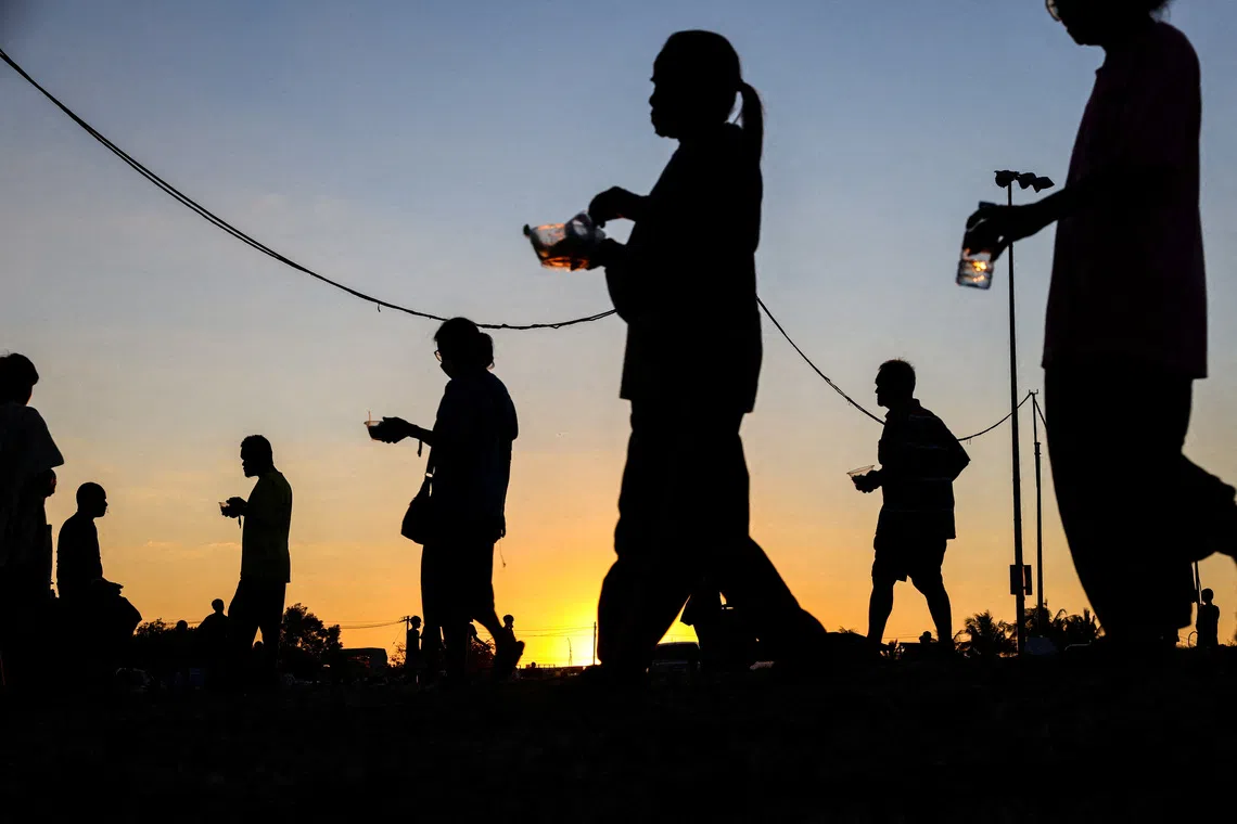 FILE PHOTO: Displaced people walk after receiving food at a temporary shelter amid clashes between Thailand and Cambodia along a disputed border area, in Buriram province, Thailand, December 16, 2025. REUTERS/Athit Perawongmetha/File Photo