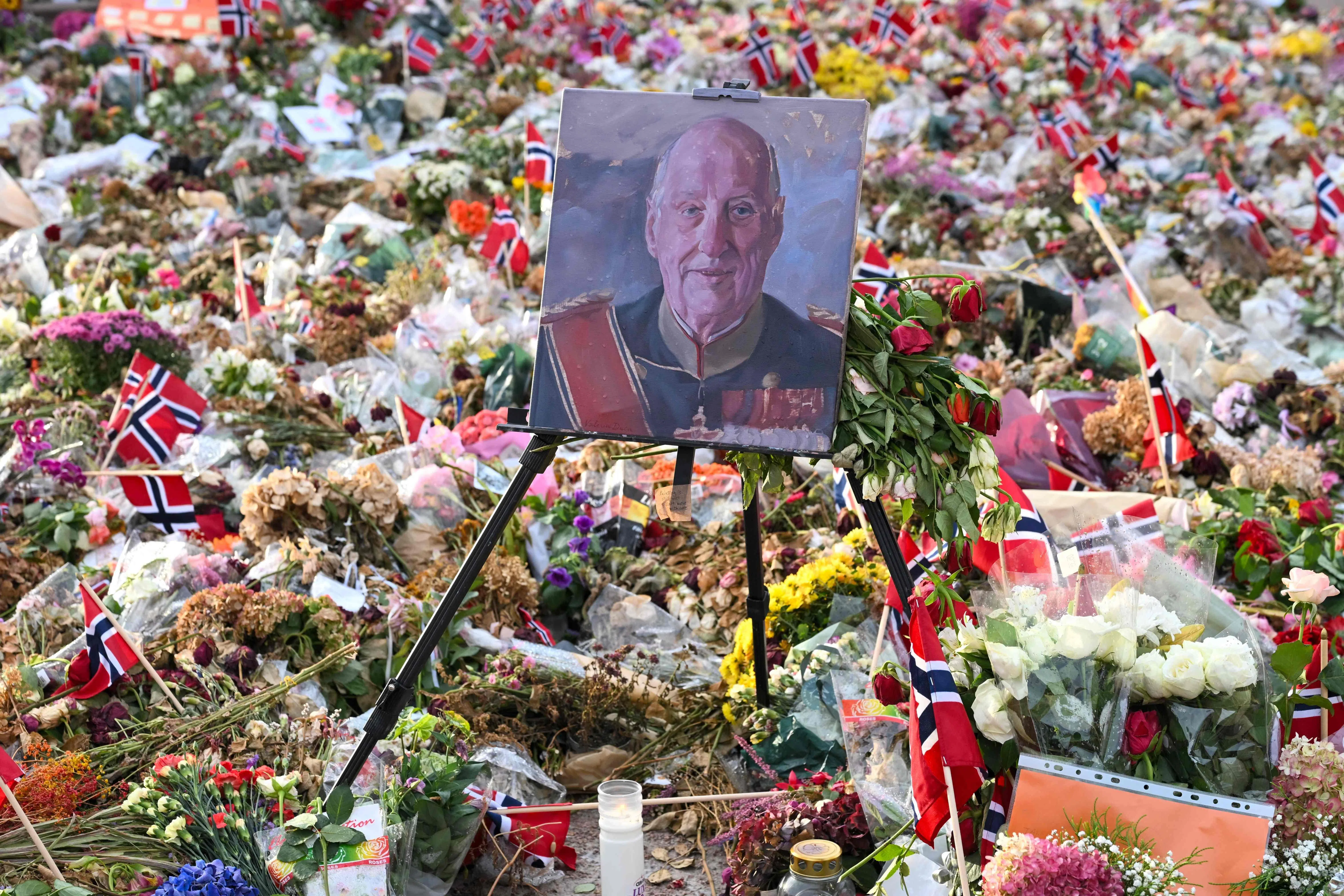 TOPSHOT - A portrait of the late King Harald V of Norway is displayed among flowers and Norwegian flags laid outside the Royal Palace in Oslo, Norway, on September 8, 2026, on the eve of his state funeral. King Harald V died on August 28, 2026 aged 89 and his coffin will be carried in a funeral procession from the Royal Palace along Karl Johans gate to Oslo Cathedral on September 9, 2026. (Photo by Nicolas TUCAT / AFP)