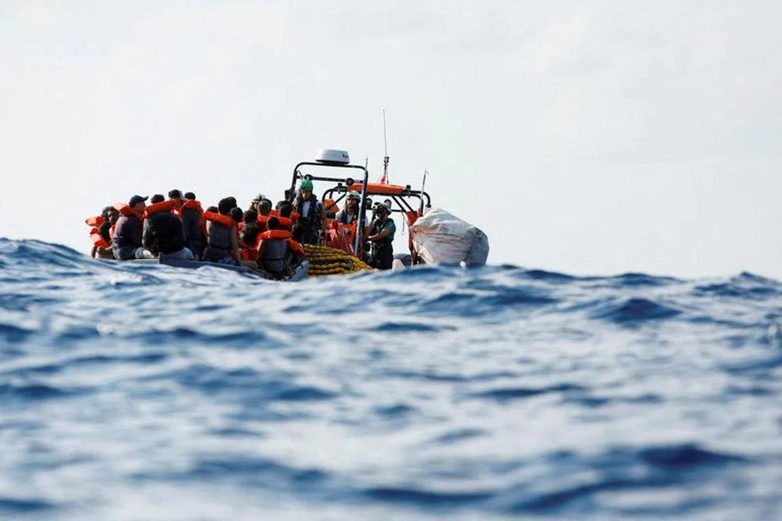 FILE PHOTO: Crew members of the Geo Barents migrant rescue ship, operated by Medecins Sans Frontieres (Doctors Without Borders), distribute life jackets to a group of 61 migrants on a wooden boat during a rescue operation in international waters off the coast of Libya, in the central Mediterranean Sea September 28, 2023. REUTERS/Darrin Zammit Lupi T/File Photo