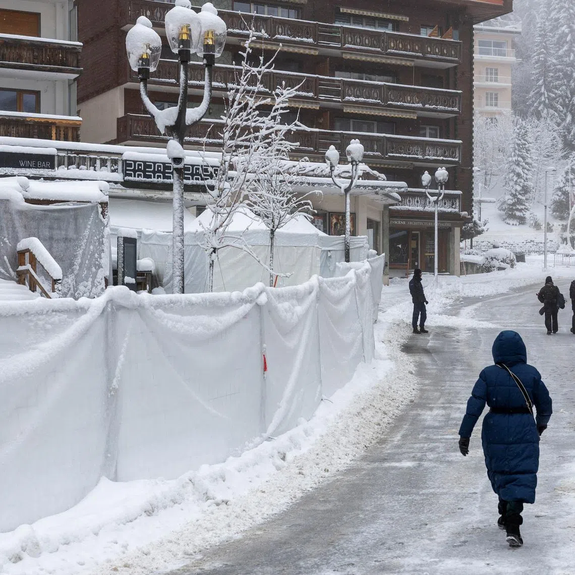 People walk past the "Le Constellation" bar following a deadly fire during a New Year's Eve party, in Crans-Montana.