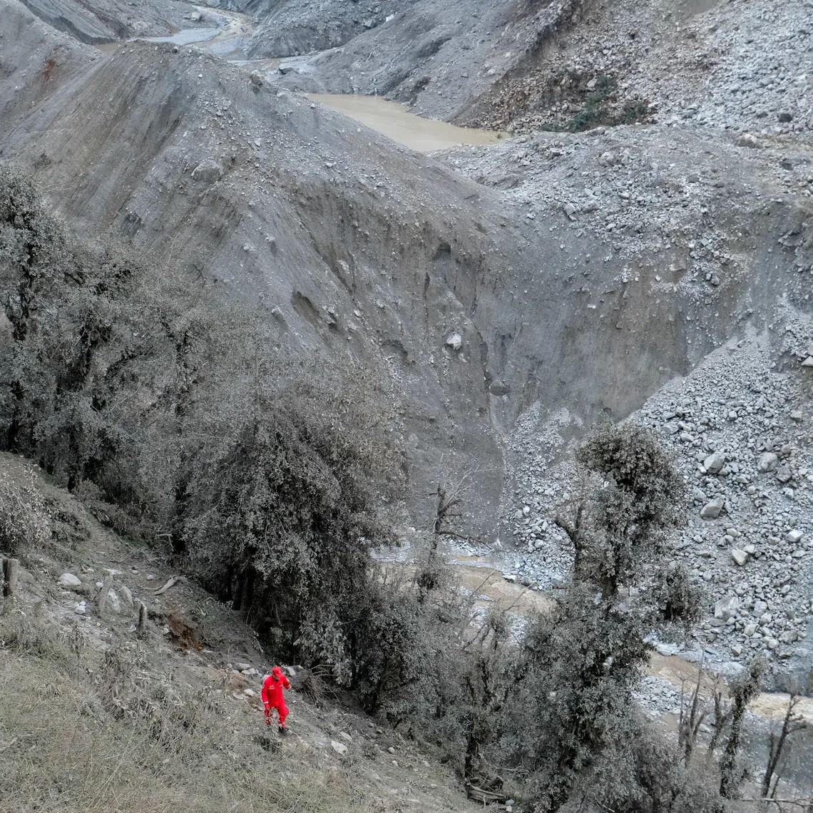 A Chinese rescue worker walks near a barrier lake formed following a mudslide.
