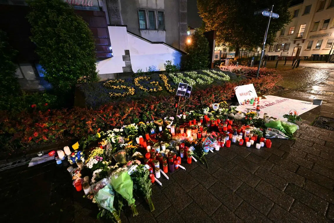 Candles and flowers and the inscription "Why? You are not alone" are pictured on Aug 24 near the area where three people were killed and several injured during a knife attack during a city festival in Solingen a day earlier.