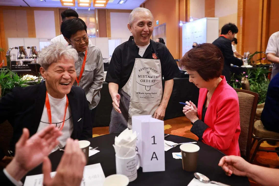 Mr Gilbert Lay, 68, who is living with dementia, taking orders from  Minister of State for Trade and Industry and Culture, Community and Youth Low Yen Ling at pop up cafe The Restaurant of Mistaken Orders. The cafe, which is debuting for the first time outside Japan, is staffed by seniors living with dementia. Seated to Ms Low's right is Japanese founder Yukio Wada, 68. 