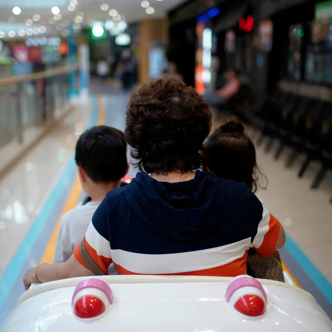 FILE PHOTO: A person sits in a toy car with children at a shopping mall in Shanghai, China June 1, 2021. REUTERS/Aly Song/File Photo