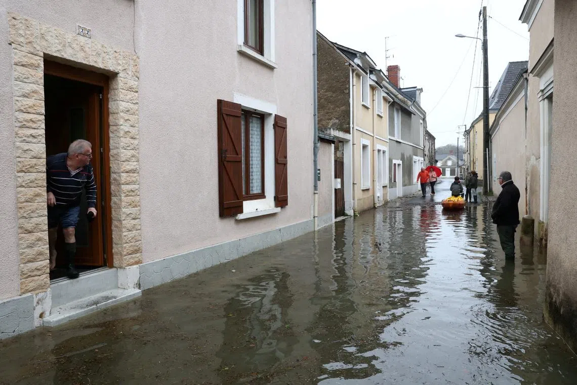 Local residents watching their flooded street in Cheffes as the River Sarthe overflows, after months of rainfall that caused flooding in western France, on Feb 18, 2026.