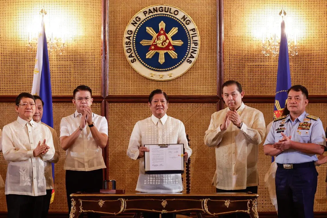 Philippine President Ferdinand Marcos Jr. holds one of two newly-signed maritime laws during ceremonies at the Malacanang Presidential Palace in Manila, Philippines, on Nov 8. 