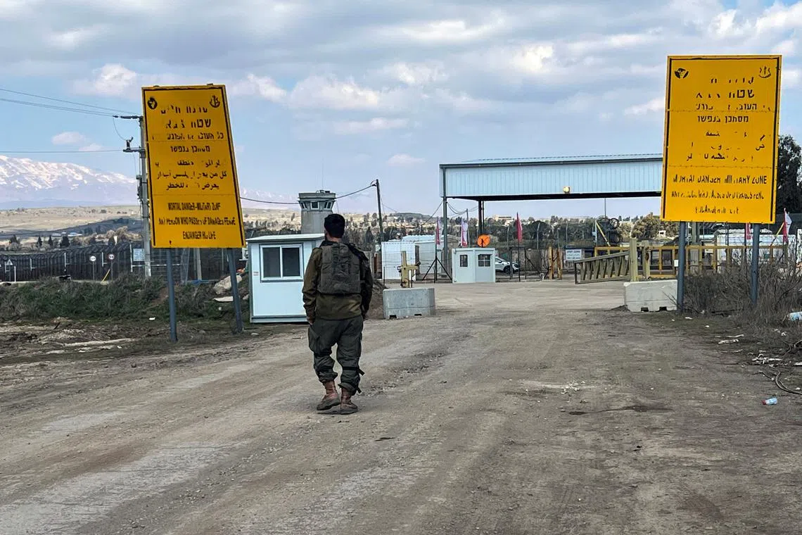 FILE PHOTO: An Israeli soldier walks by the fence of the ceasefire line by Syria and the Israeli-occupied Golan Heights, at Quneitra crossing in the Golan Heights March 2, 2025. REUTERS/Avi Ohayon/File Photo