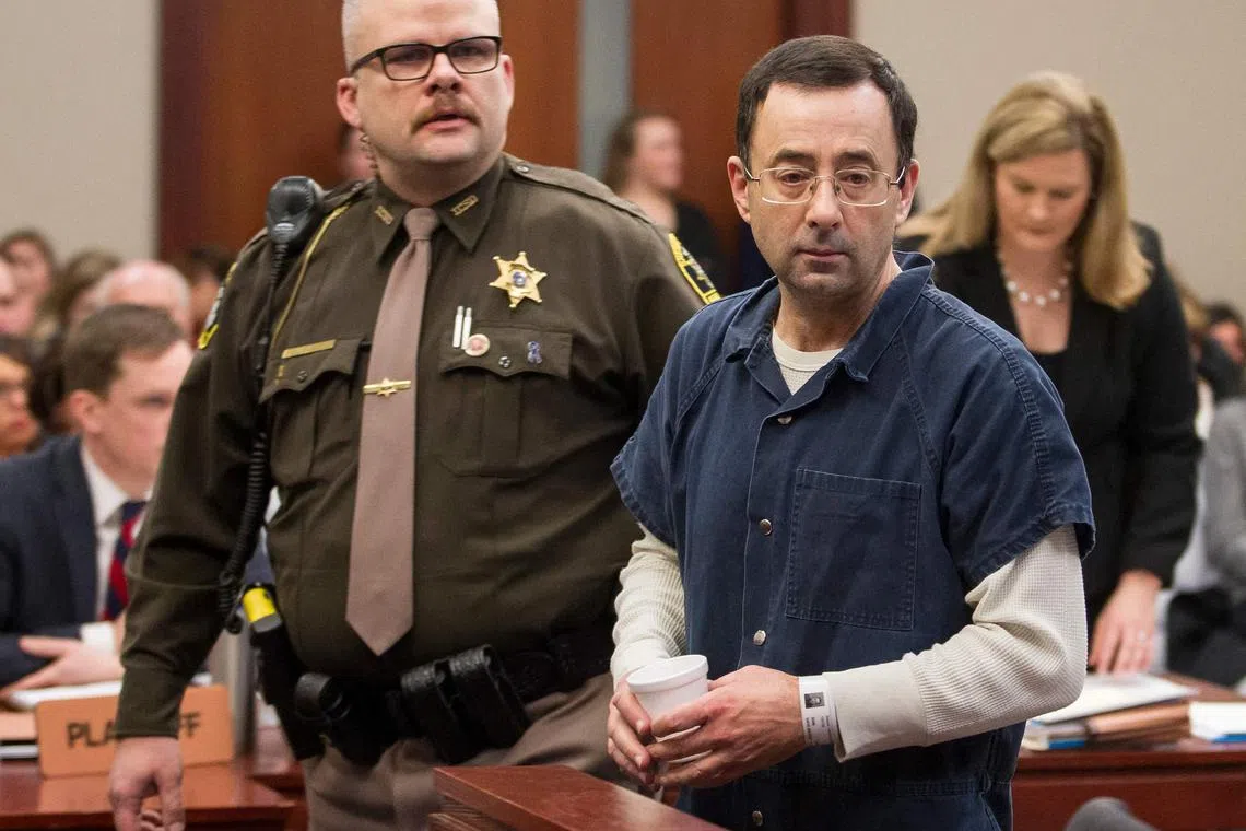 A 2018 photo shows Larry Nassar being led to the witness box during his sentencing hearing in Lansing, Michigan.