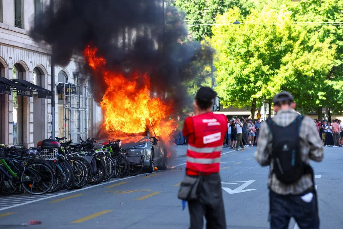 Protesters smash windows and set Tesla ablaze in anti-G7 march in Geneva