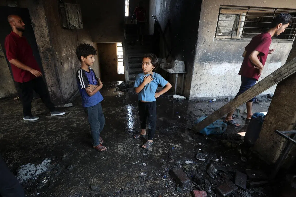 Palestinian children stand at the site of an Israeli strike on a school sheltering displaced people, in Gaza City, July 25, 2025. REUTERS/Mahmoud Issa