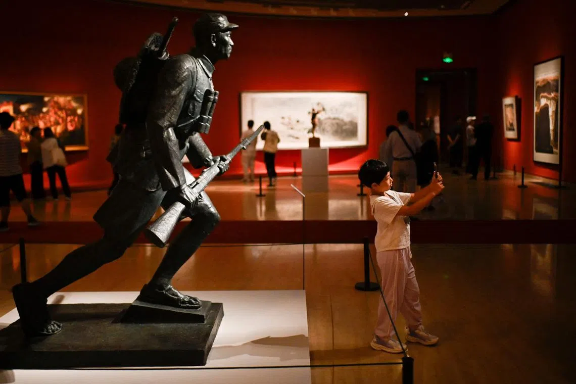 A child takes a selfie with the Nameless Hero Warrior during an exhibition commemorating the 80th anniversary of the end of World War II at the National Art Museum of China in Beijing on Aug 26.