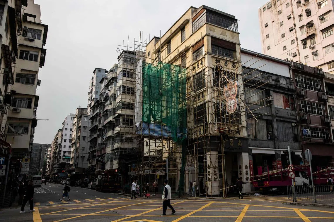 Workers (C) constructing bamboo scaffolding around the Nam Cheong Pawn Shop neon sign before its removal at the requests of the government because of a change in regulations surronding neon signs., March 9, 2023. 