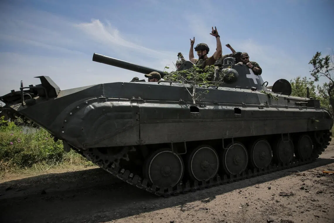 Ukrainian servicemen ride a BMP-1 infantry fighting vehicle near the front line, in the newly liberated village of Neskuchne, in Ukraine's Donetsk region.