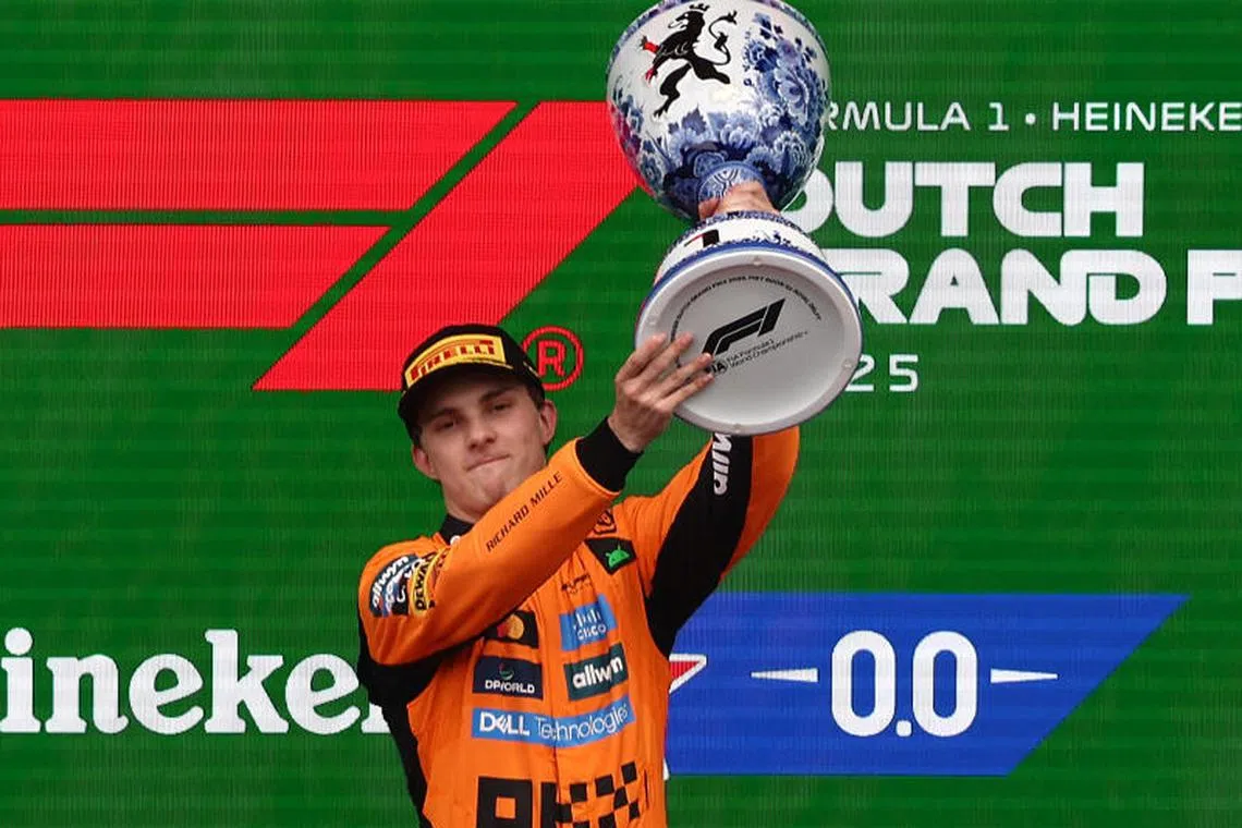McLaren's Oscar Piastri celebrates on the podium with a trophy after winning the Dutch Grand Prix.