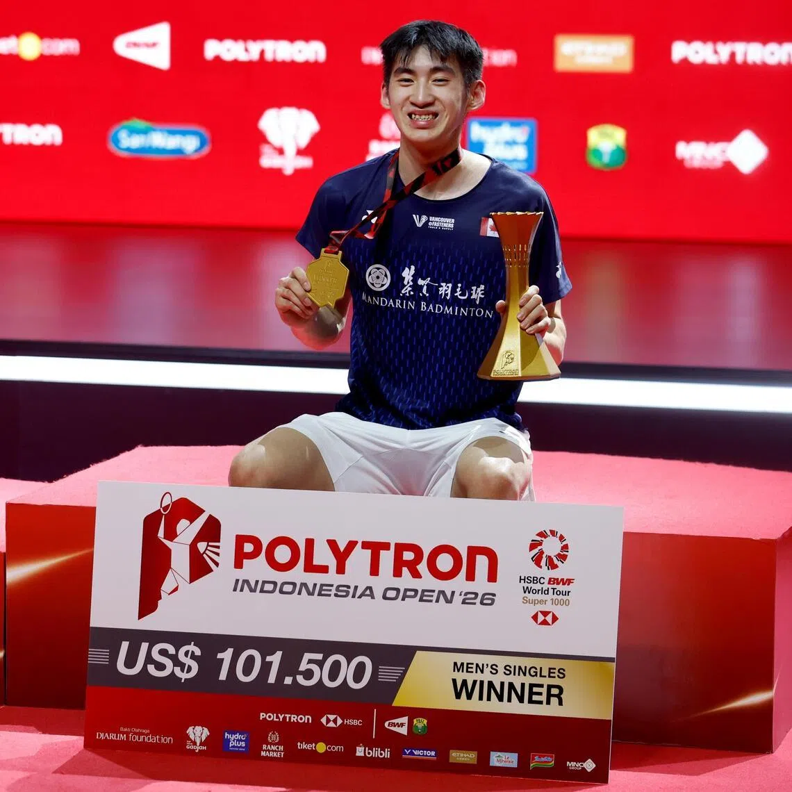 Canada's Victor Lai posing with his medal and trophy after winning the men's singles title at the Indonesia Open on June 7.