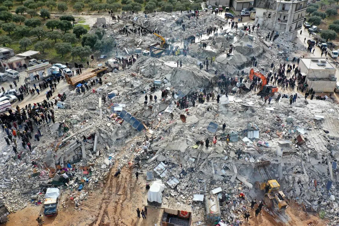 This aerial view shows residents searching for victims and survivors amidst the rubble of collapsed buildings following an earthquake in the village of Besnia near the town of Harim, in Syria's rebel-held northwestern Idlib province on the border with Turkey, on Feb 6, 2023.  