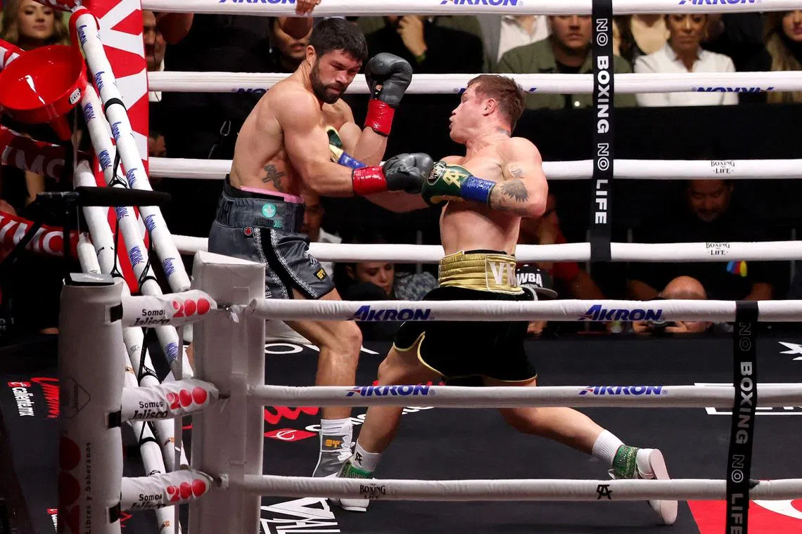 Mexican Saul "Canelo" Alvarez punching Briton John Ryder in their WBA, WBC, IBF and WBO super middleweight fight in Guadalajara, Mexico on May 6, 2023.
