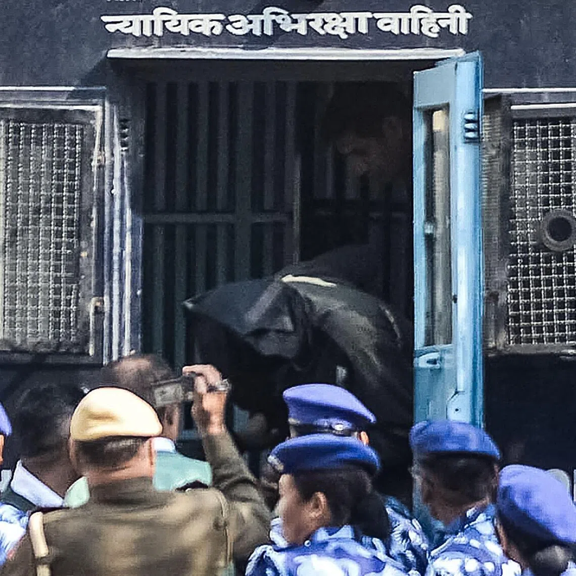 Security personnel escort suspect Amir Rashid Ali from a police vehicle at the Patiala House Court.