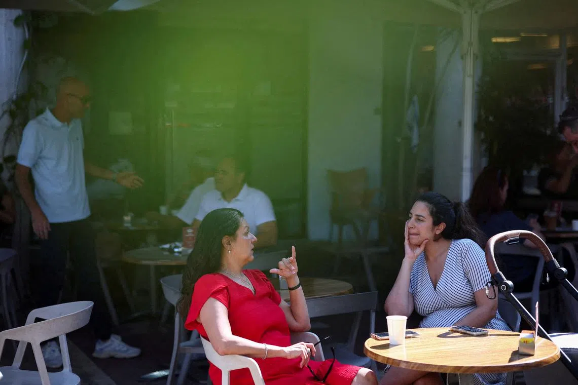 Israelis sit at a cafe, after U.S. President Donald Trump announced a ceasefire between Israel and Iran, in Haifa, Israel, June 25, 2025. REUTERS/Florion Goga     REFILE - CORRECTING  LOCATION FROM \"TEL AVIV\" TO \"HAIFA\".  TPX IMAGES OF THE DAY