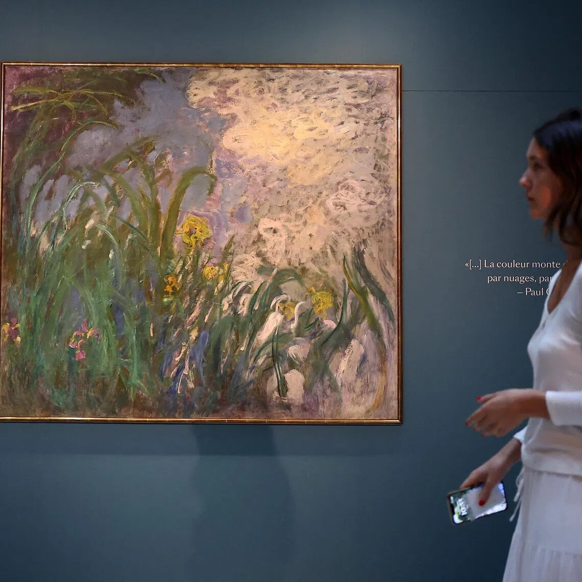 A visitor walks past Claude Monet’s “Iris” on display at Sotheby’s auction house in Paris.