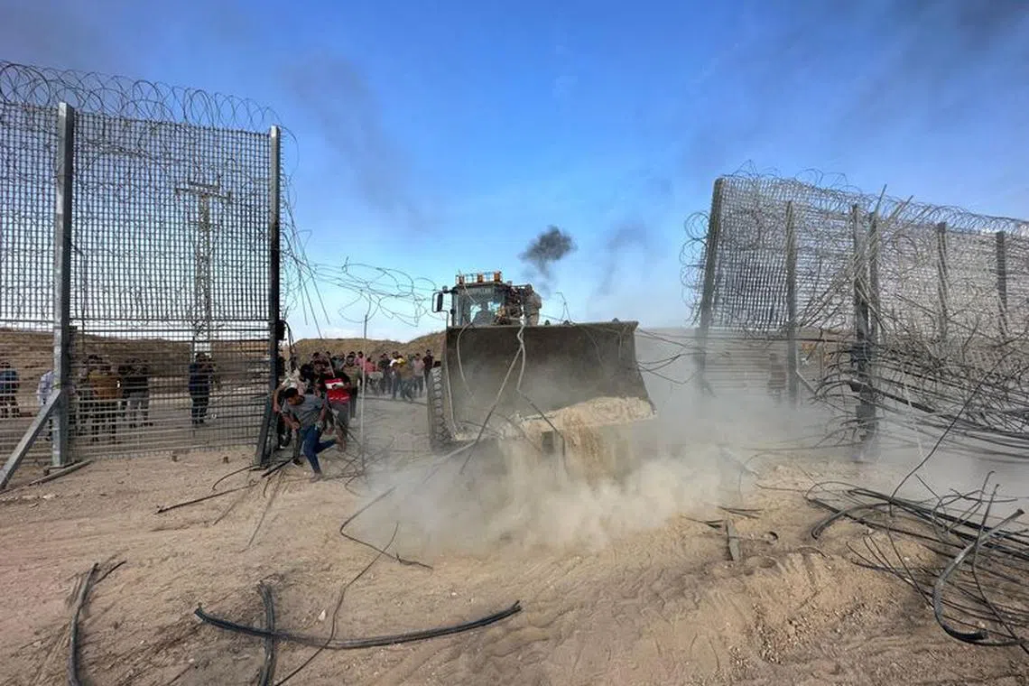 FILE PHOTO: Palestinians break into the Israeli side of Israel-Gaza border fence after gunmen infiltrated areas of southern Israel, October 7, 2023. REUTERS/Mohammed Fayq Abu Mostafa/File Photo