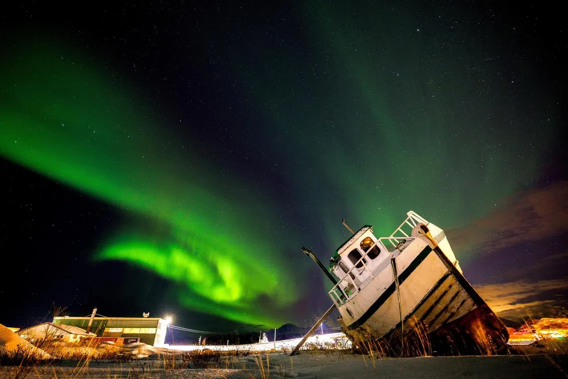 Northern Lights, also called Aurora Borealis, illuminating the night sky over a boat on the shore in Sommaroy, Norway on Nov 19, 2023. 