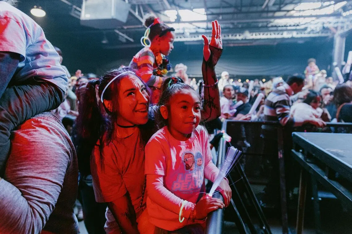 Maria Sabangan listens with her daughter Avianna, 5, as Lenny Pearce takes the stage for the ‘baby rave’ in San Francisco, Nov. 22, 2025. Everyone loves tiny dancers. Now some artists are considering why they bring us such joy — and what lessons they might have for grown-ups. (Jason Henry/The New York Times)