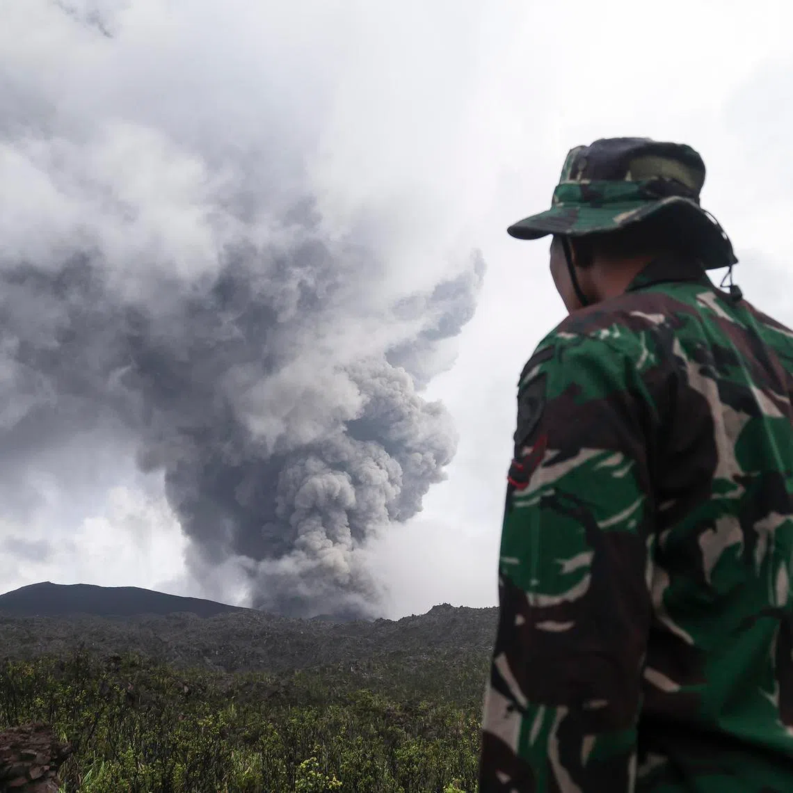 epa12943719 A rescuer looks on Mount Dukono Volcano during its eruption in North Halmahera, Indonesia, 09 May 2026. According to the Indonesia’s rescue agency (Basarnas), the rescuers have recovered the body of an Indonesian hiker while two Singaporean hikers remain missing. EPA/NIZAM