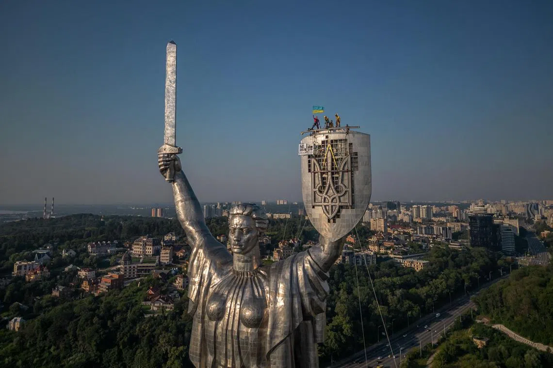Steeplejacks wave the Ukrainian flag after installing Ukraine's coat of arms on the shield of the 62m-tall Motherland Monument in Kyiv, in August 2023. The Ukrainian trident has replaced the coat of arms of the former Soviet Union.