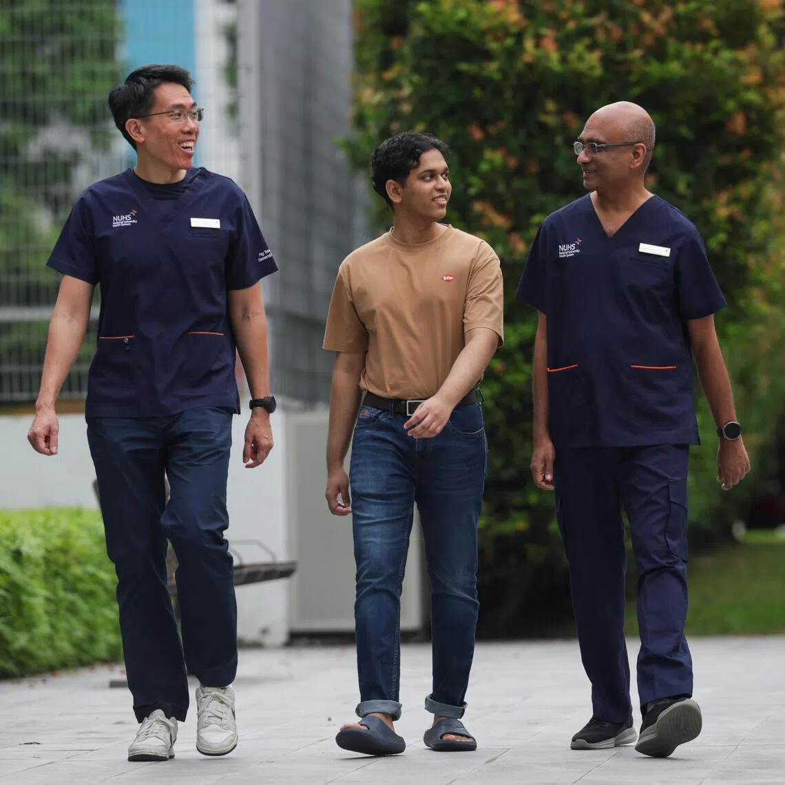 Strolling around the grounds of Ng Teng Fong General Hospital (NTFGH) with his doctors (left) Low Shiong Wen, who heads the Neurosurgery, and anesthetist Harinda Goonesekera (right). Slow walk was something Arshad could not do two years ago.