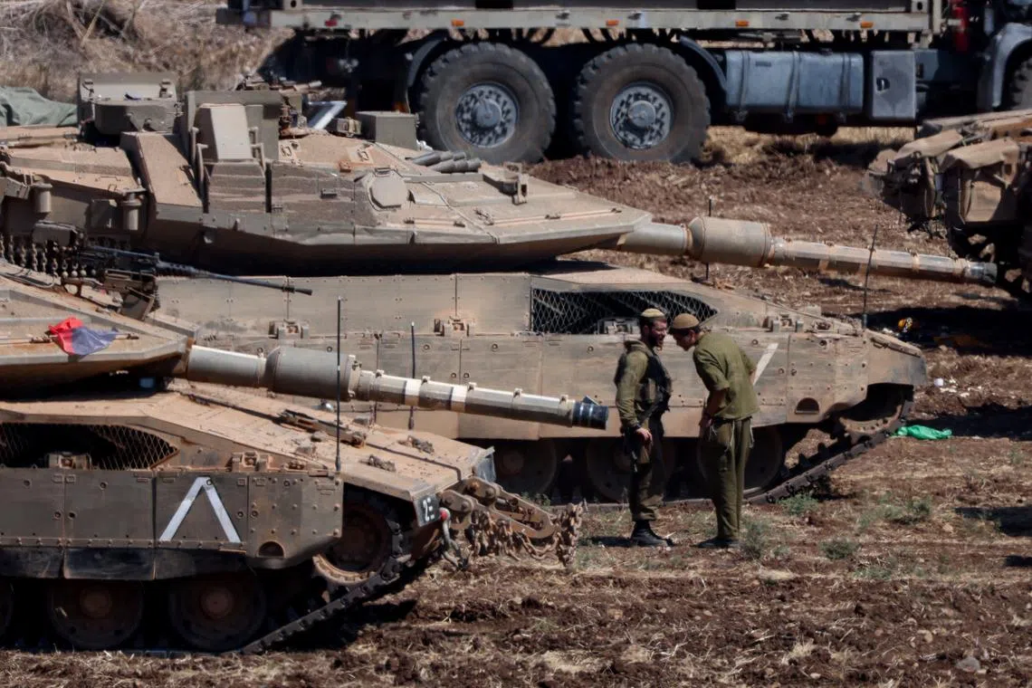 Israeli members of the military stand next to armoured vehicles, amid cross-border hostilities between Hezbollah and Israel, in northern Israel, September 30, 2024. REUTERS/Jim Urquhart