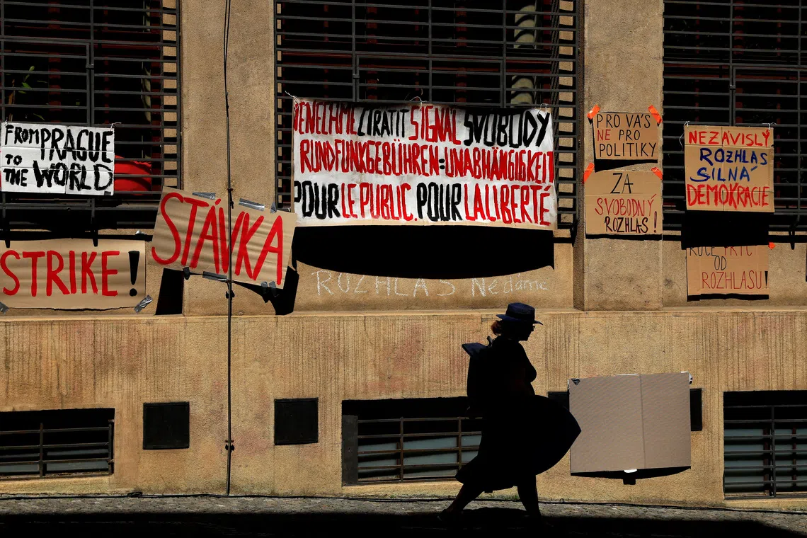 FILE PHOTO: A woman walks past placards hanging on a building of Czech Radio as employees of public broadcasters strike in protest of the government's planned overhaul of public media funding, in Prague, Czech Republic, June 22, 2026. REUTERS/David W Cerny/File Photo