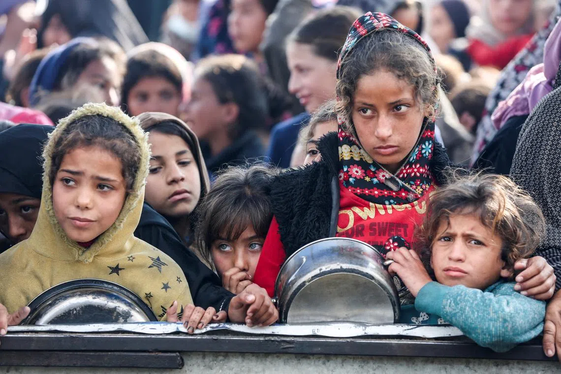 Palestinians gather to receive food cooked by a charity kitchen, before a ceasefire between Hamas and Israel takes effect, in Khan Younis, in the southern Gaza Strip, January 17, 2025. REUTERS/Hatem Khaled