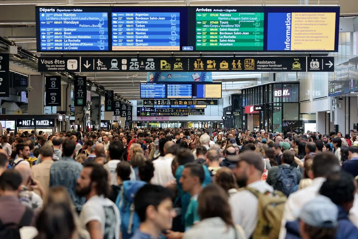 Passengers gather around the departure and arrival boards at the Gare Montparnasse train station in Paris on July 26.