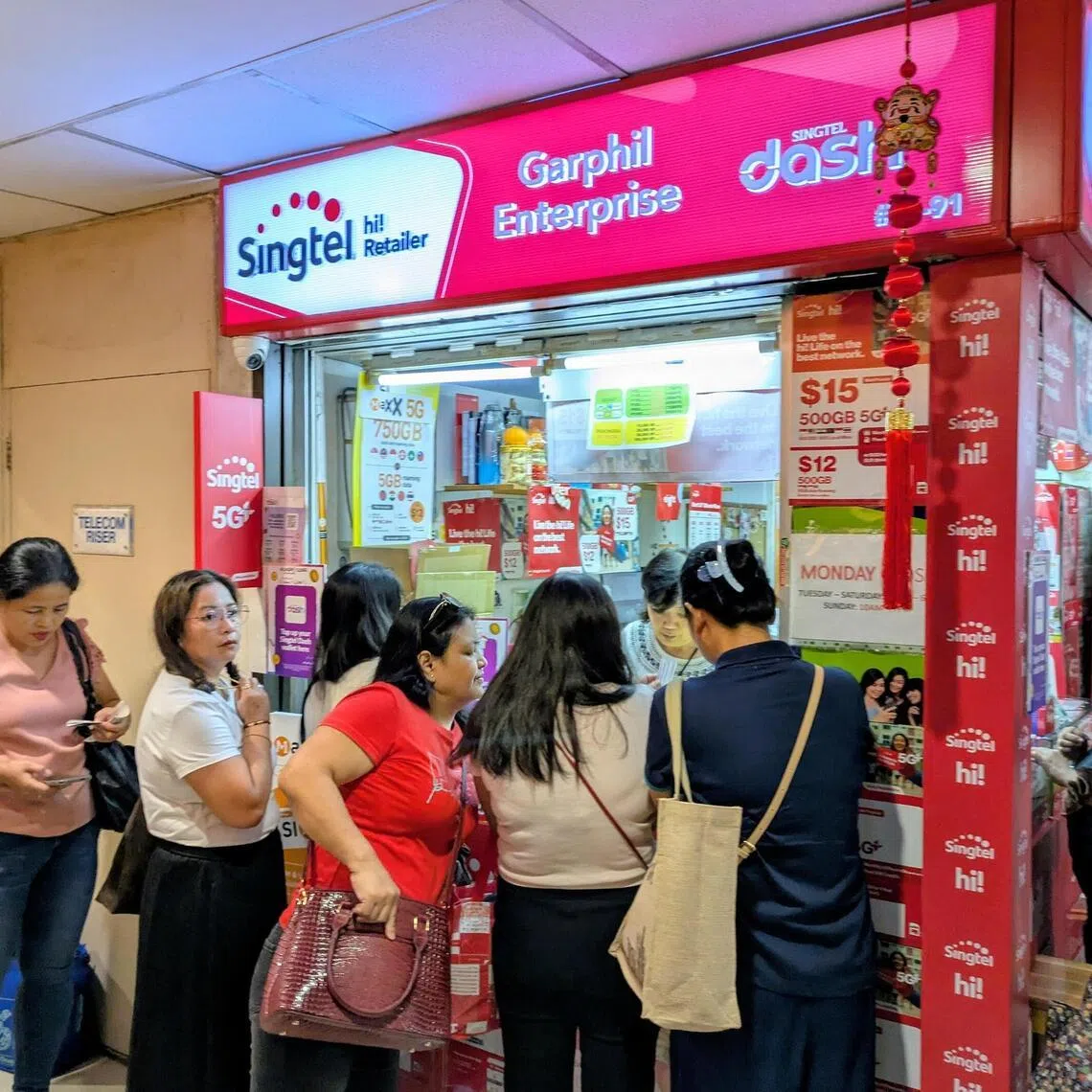 Foreign domestic workers queue to top up their prepaid SIM cards at Lucky Plaza.
