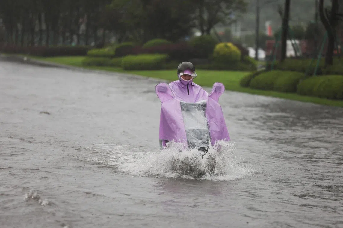 A person rides an electric scooter through a flooded road after heavy rain brought by Typhoon Bavi in Wenzhou, Zhejiang province, China.